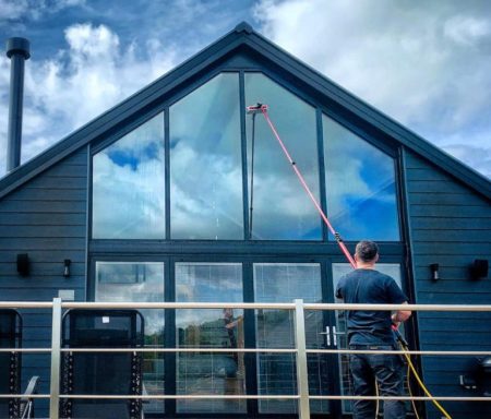 Nettoyage des vitres à PRINGY en HAUTE-SAVOIE Un homme nettoie une grande fenêtre dans une maison moderne.