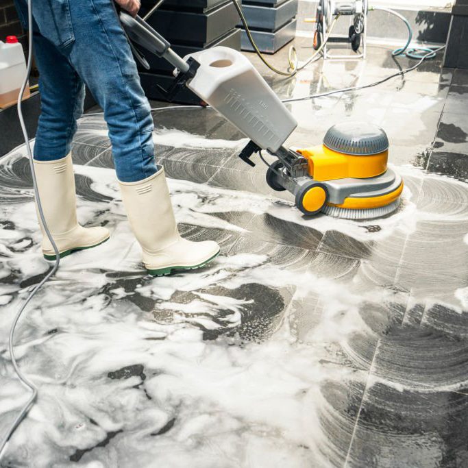 Décrassage et nettoyage de sols dans tous types de locaux en Haute-Savoie et Savoie Un technicien de nettoyage de la société de nettoyage 74 NETT utilise une monobrosse pour décrasser et nettoyer un sol carrelé d'un magasin